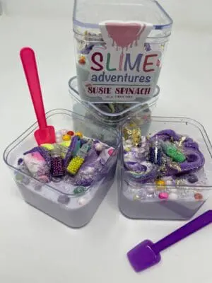 A table with two containers of slime and some other items.
