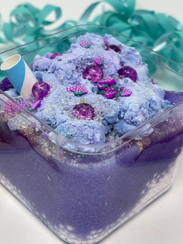 A bowl of blue ice cream with purple flowers.