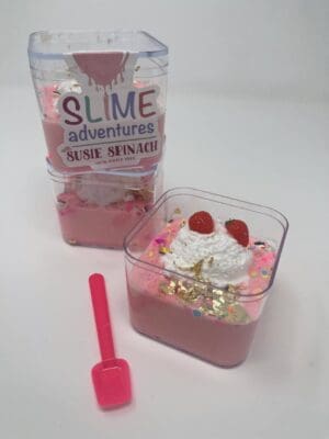 A pink container filled with food next to a bottle of slime.
